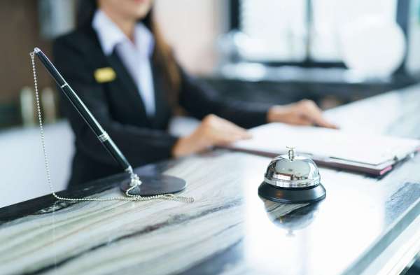 Hotel,Receptionist,In,Uniforms,At,Desk,In,Lobby,Friendly,And